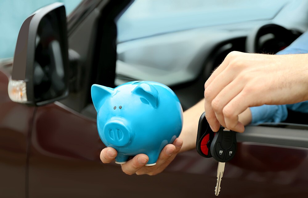 Man holding piggy bank and key in his new car