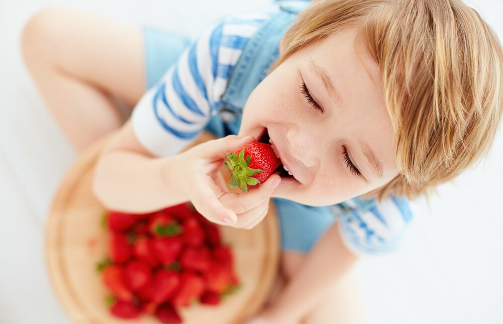 cute happy kid eating tasty ripe strawberries