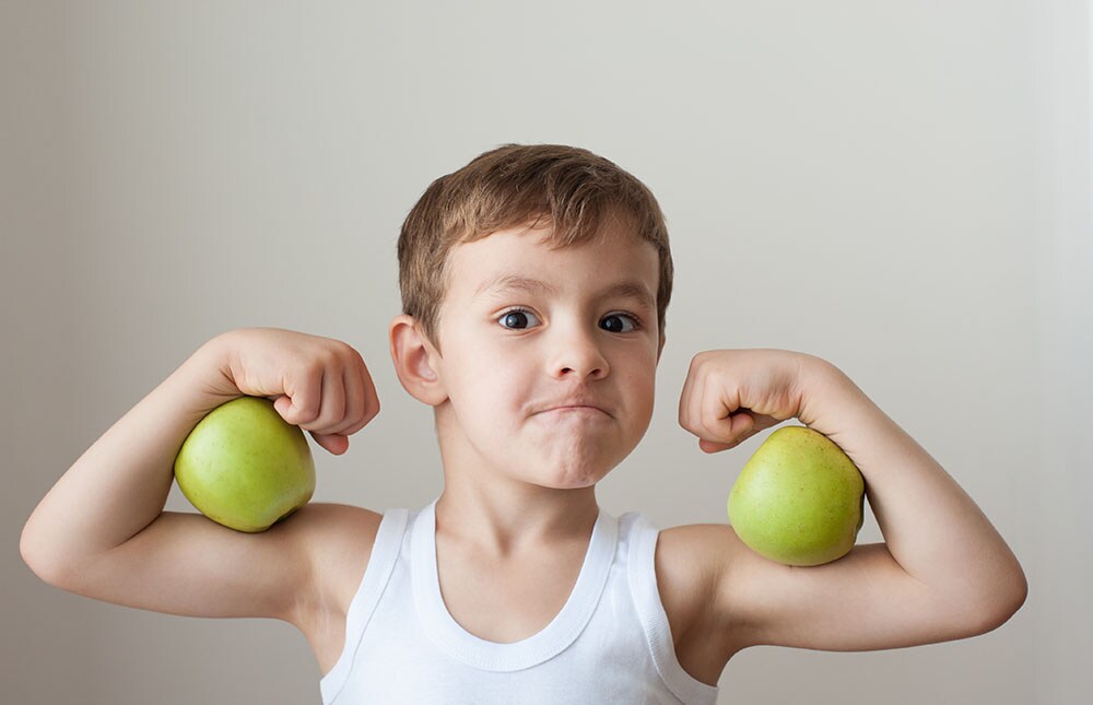 boy with green apples showing biceps